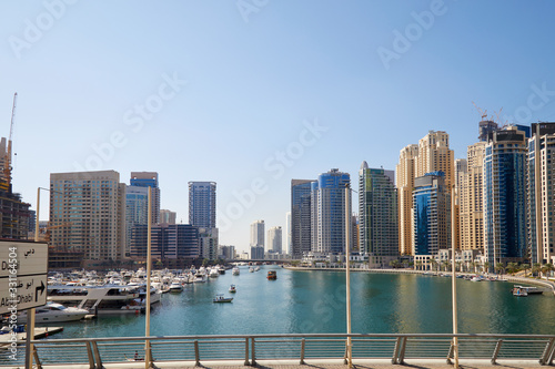 Dubai Marina skyscrapers and boats in harbor in a sunny day, clear blue sky in Dubai, United Arab Emirates