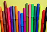 multicolored markers for drawing on a yellow paper background