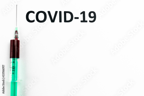COVID-19 napis na białej kartce, strzykawka z krwią, test, epidemia