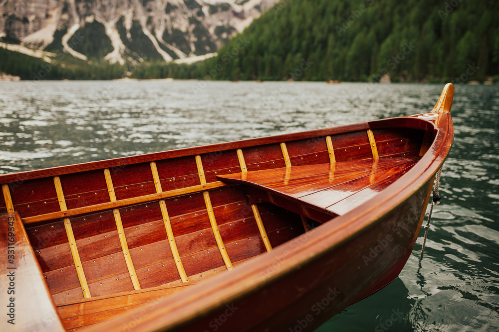 Obraz premium Lake Braies, wooden boat on a mountain lake, nature and travel. Wooden boat at Lago di Braies. Tourist boat near old wooden dock house with pier on emerald surface lake water of Lago di Braies.
