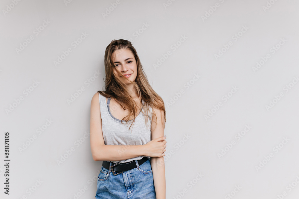 Winsome caucasian girl in casual attire posing in studio. Gorgeous long-haired young woman with lightly-tanned skin isolated on light background. Winsome caucasian girl in casual attire posing in studio. Gorgeous long-haired young woman with lightly-tanned skin isolated on light background.