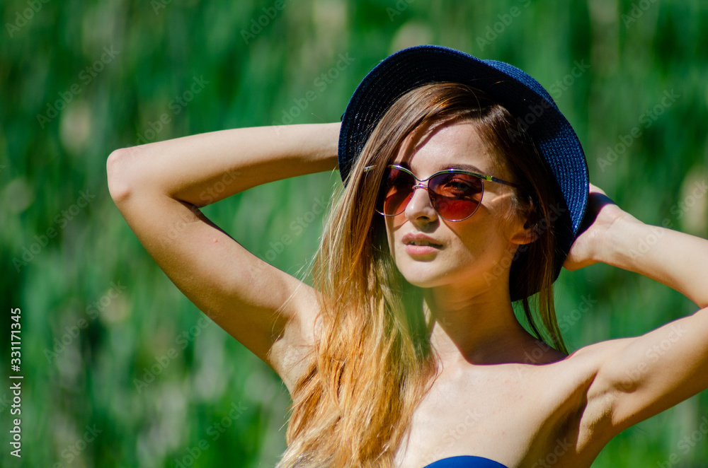 Girl in a hat and glasses in a swimsuit posing on the beach Girl in a hat and glasses in a swimsuit posing on the beach