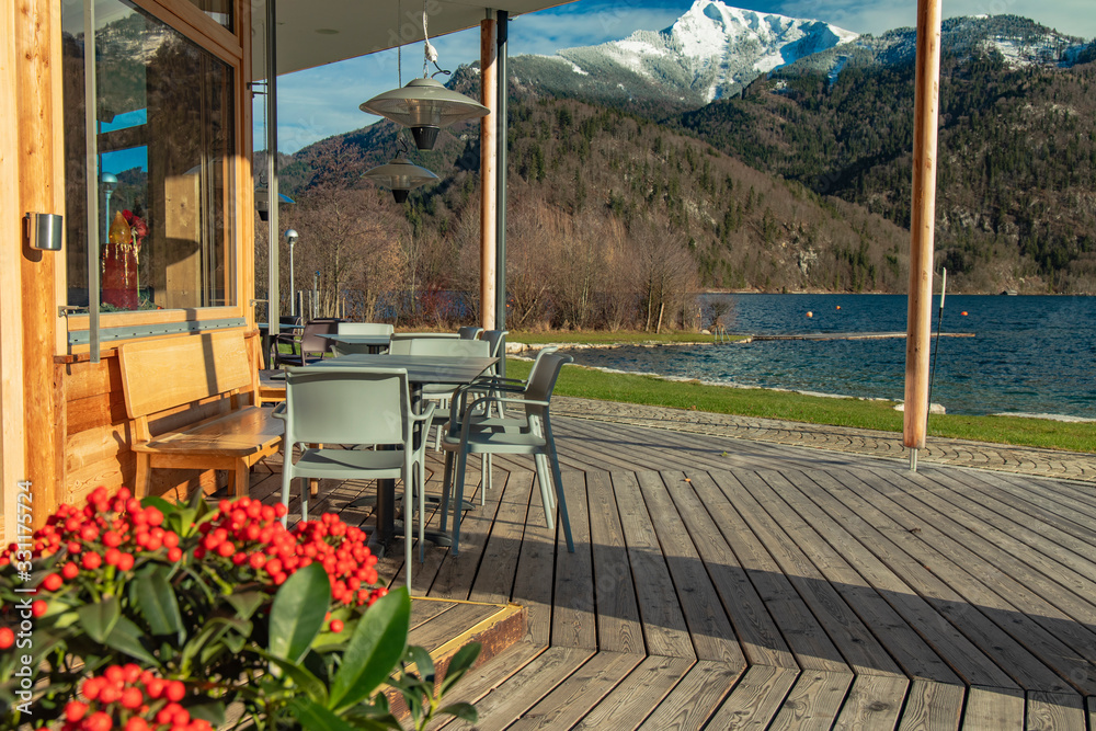 Fototapeta premium patio restaurant outside porch space empty table without people flowers foreground with scenic picturesque background view on Alps mountains