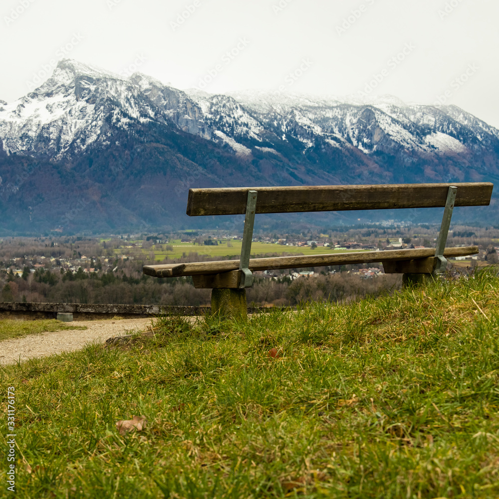 empty wooden bench on a hill with picturesque landscape scenic view on snowy Alps mountain ridge background