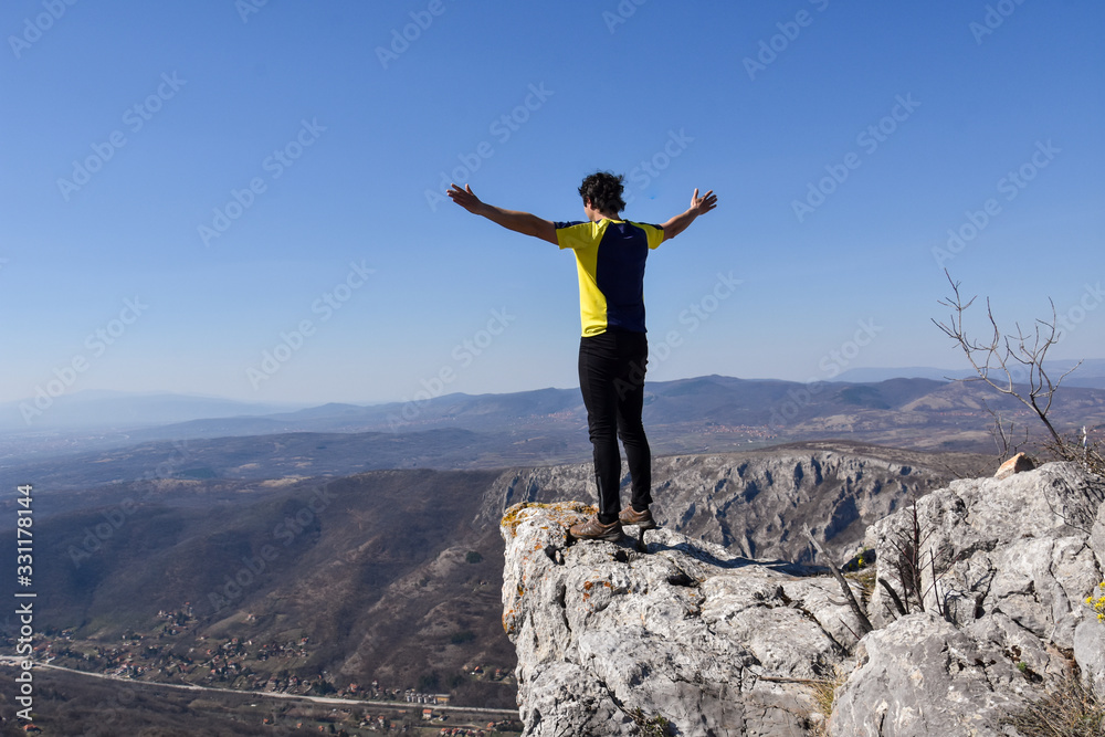 Man rise a hands on top of the mountain. Concept of freedom. Young man enjoy on a cliff edge