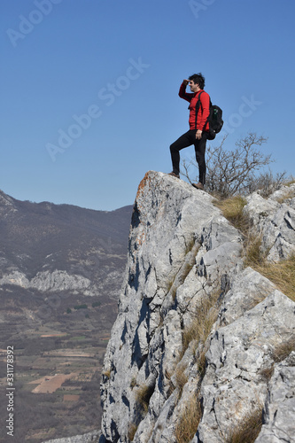 Young man on a cliff edge on the top of mountain with gorgeous view. Dangerous Place. Adrenaline. Beautiful mountain landscape