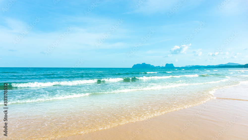 Clean white beach golden brown sand and blue sea under clear blue sky in a sunny day, mountain on background