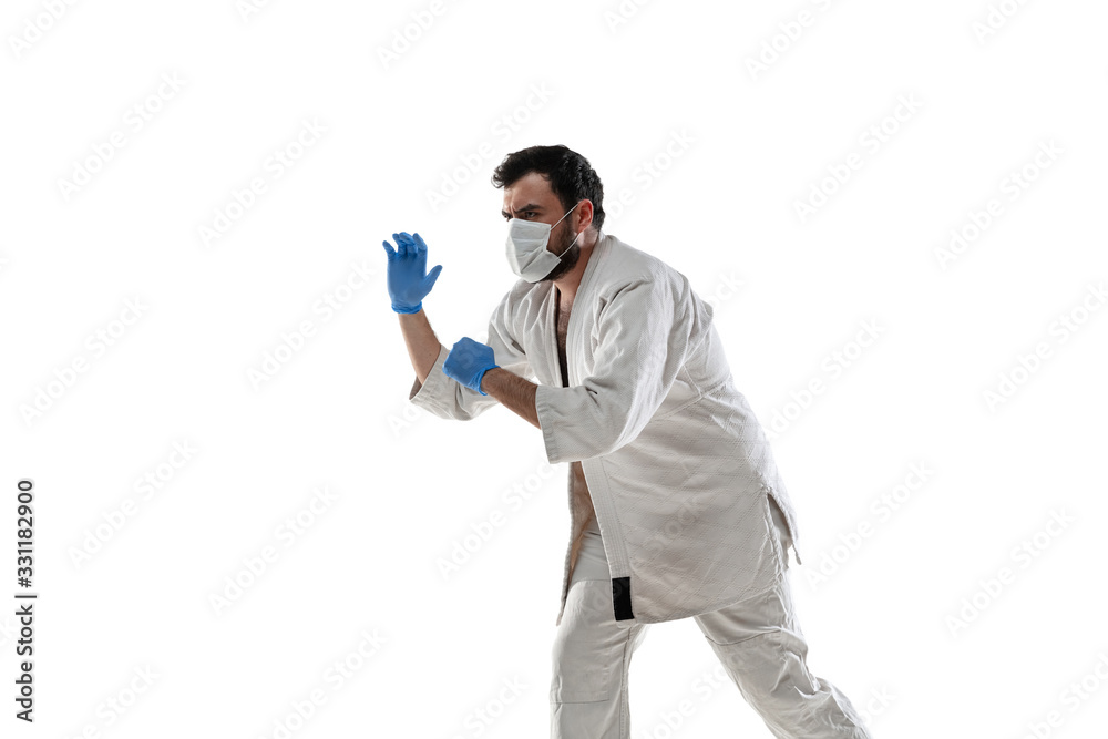 Punching virus. Martial arts fighter in protective mask and gloves. Prevention against pneumonia. Still active while quarantine. Chinese coronavirus treatment. Healthcare, medicine, sport concept. Punching virus. Martial arts fighter in protective mask and gloves. Prevention against pneumonia. Still active while quarantine. Chinese coronavirus treatment. Healthcare, medicine, sport concept.