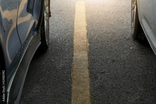 The side of a shiny cars on the asphalt road white yellow line. © thongchainak