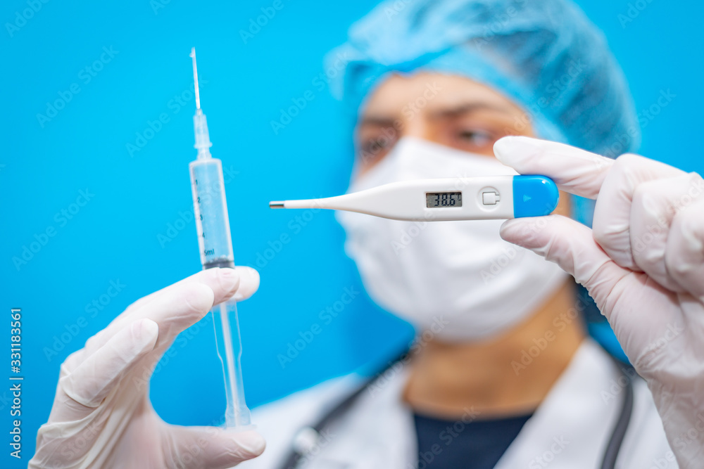 Medical laboratory syringe and high temperature thermometer in hands of young virologist female doctor, concept of pandemia, epidemic, spread of coronavirus. Covid-19 worldwide protection vaccine. Medical laboratory syringe and high temperature thermometer in hands of young virologist female doctor, concept of pandemia, epidemic, spread of coronavirus. Covid-19 worldwide protection vaccine.
