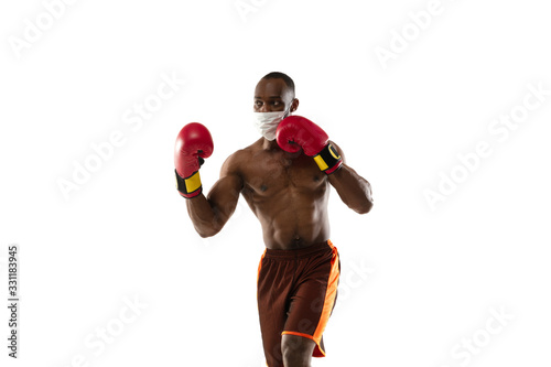 Beat off the virus. African-american boxer in protective mask, gloves. Prevention against pneumonia. Still active while quarantine. Chinese coronavirus treatment. Healthcare, medicine, sport concept. photo