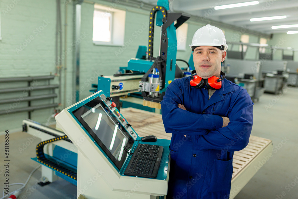 CNC machine operator in the Hard white Hat Walks Through Light Modern Factory While Holding tablet. Successful, Handsome Man in Modern Industrial Environment. CNC machine operator in the Hard white Hat Walks Through Light Modern Factory While Holding tablet. Successful, Handsome Man in Modern Industrial Environment.
