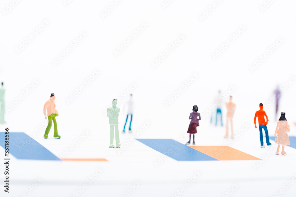 Selective focus of people figures on surface with graphs isolated on white, concept of equality Selective focus of people figures on surface with graphs isolated on white, concept of equality