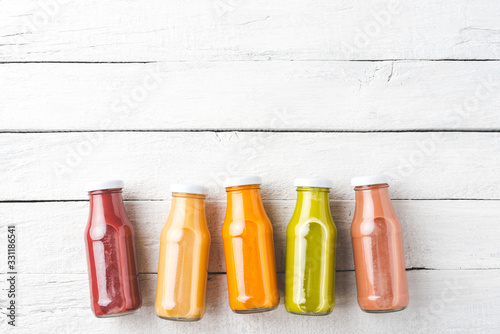 Colourful juices on white wooden table with copyspace. Fresh smoothies in bottles