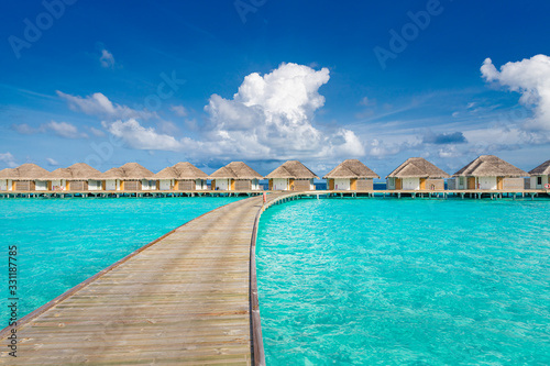 Water villas bungalows and wooden bridge at Tropical beach in the Maldives at summer day
