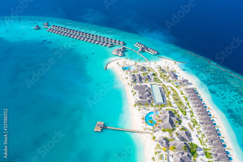 The drone photo with a wooden water villas seen from above and an amazing blue lagoon crystal clear water close to tropical lagoon. Amazing summer travel and vacation background. Dreamy beach scenery