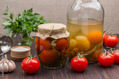 Glass jar of canned tomatoes, fresh tomatoes, green parsley, garlic and spices