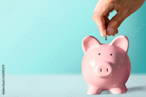 Businessman putting coin into the piggy bank photo