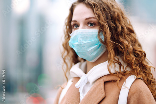 Girl in protective sterile medical mask on her face on the street. Woman, wear face mask, protect from infection of virus, pandemic, outbreak and epidemic of disease in quarantine city. Corona virus.