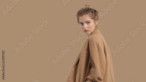 model in studio on brown background turns to the camera, oversize jacket fashion glamour look