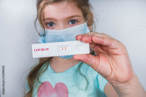 Worldwide coronavirus epidemic concept. Pandemic COVID-19, 2019-nCoV. Kid girl with positive test strip for antibody or sars-cov-2 virus disease in hands. White background photo