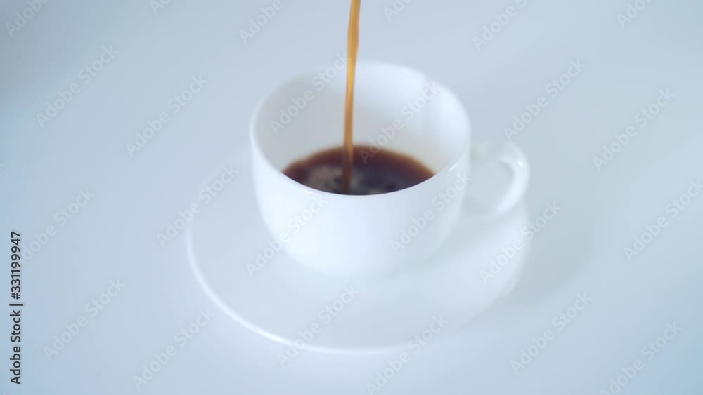 close-up of coffee being poured into a white Cup on a white table