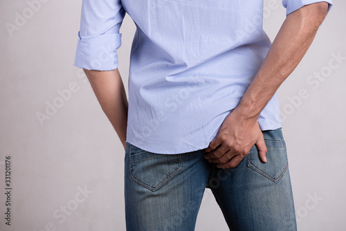 Young man hand holding her bottom because having abdominal pain and hemorrhoids, Health care concept. Man with hemorrhoids and constipation.