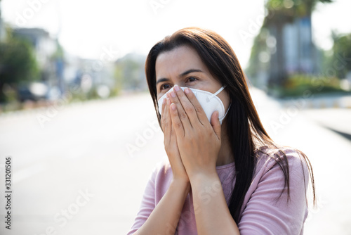 Close up of a woman in a suit wearing Protective face mask and cough, get ready for Coronavirus and pm 2.5 fighting against beside road in background.