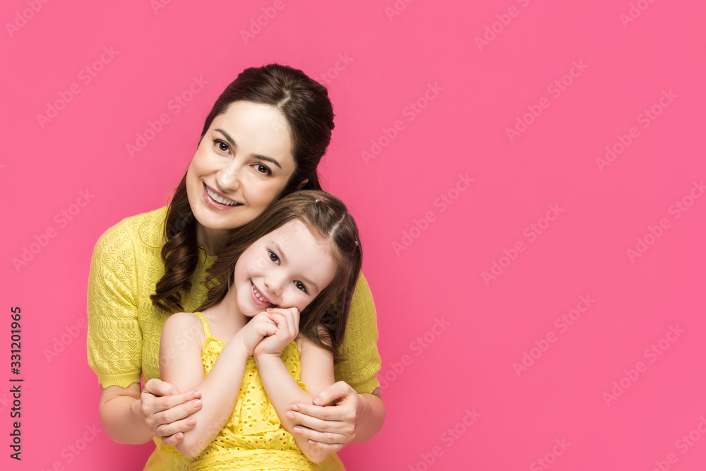 cheerful mother hugging cute daughter isolated on pink cheerful mother hugging cute daughter isolated on pink