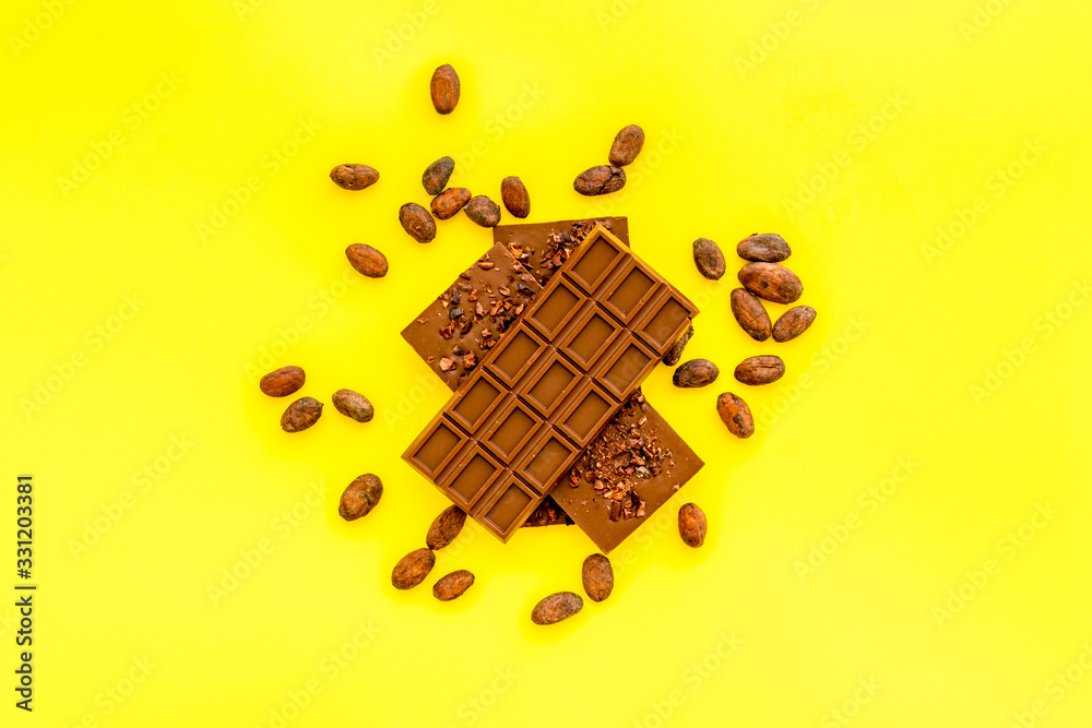 Chocolate - stack of dark bars - on yellow background top-down copy space
