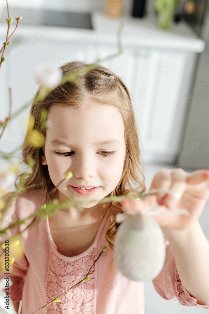 Selective focus of cute kid near willow brunches with decorative easter egg Selective focus of cute kid near willow brunches with decorative easter egg