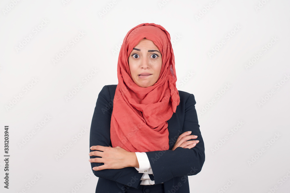 Isolated portrait of stylish young European woman bitting her mouth and looking worried and scared crossing arms, worry and doubt. Isolated portrait of stylish young European woman bitting her mouth and looking worried and scared crossing arms, worry and doubt.