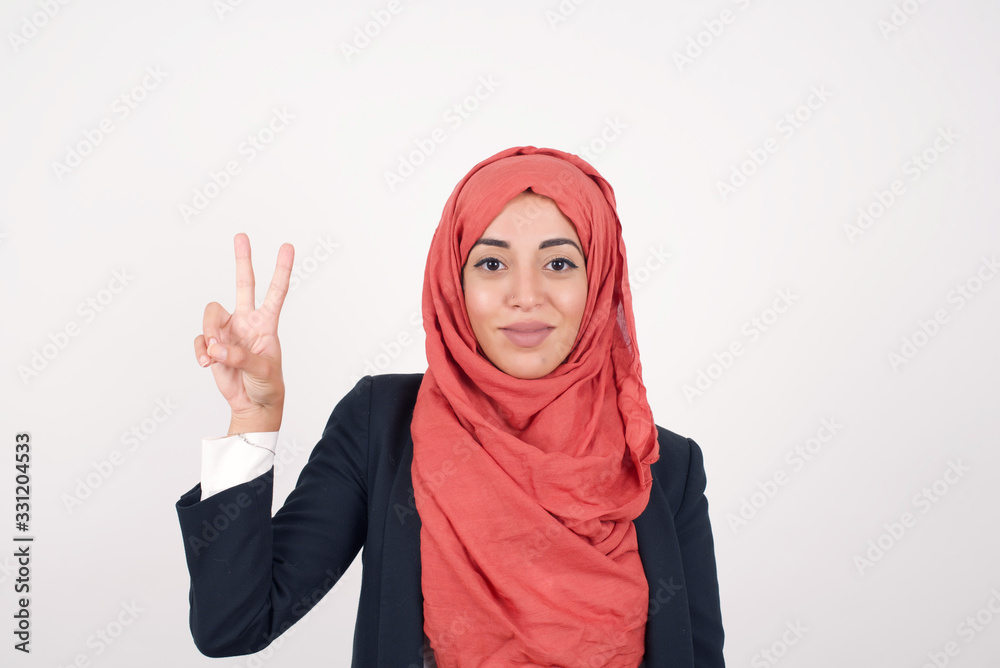 Young caucasian woman standing against gray wall showing and pointing up with fingers number two while smiling confident and happy. Young caucasian woman standing against gray wall showing and pointing up with fingers number two while smiling confident and happy.