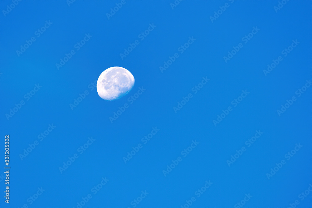 Bright growing moon in the clear blue sky. Earth satellite in space. Nature background. Astronomy and science Bright growing moon in the clear blue sky. Earth satellite in space. Nature background. Astronomy and science