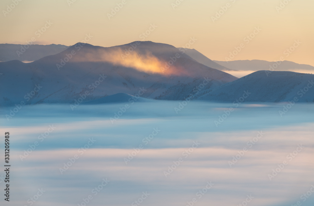 Winter landscape in foggy day at sunrise. A rainbow in mountains on Olchansky pass in Oymyakon, Sakha Republic, Russia. Top view