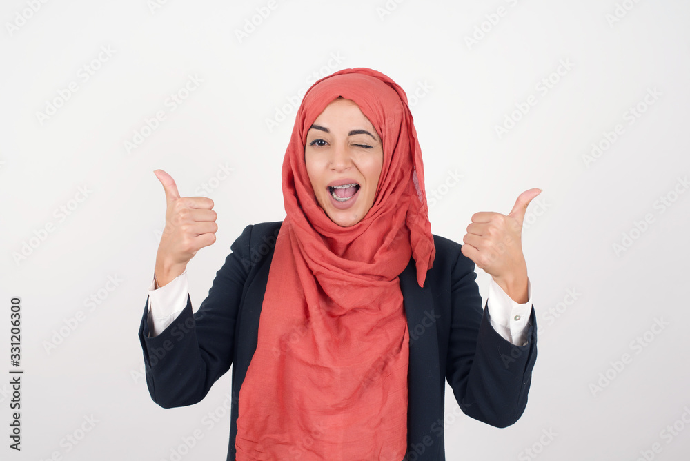 Closeup of young optimistic female isolated on grey background showing thumbs up with positive emotions of content and happiness. Copyspace, concept of satisfaction with quality and recommendation. Closeup of young optimistic female isolated on grey background showing thumbs up with positive emotions of content and happiness. Copyspace, concept of satisfaction with quality and recommendation.