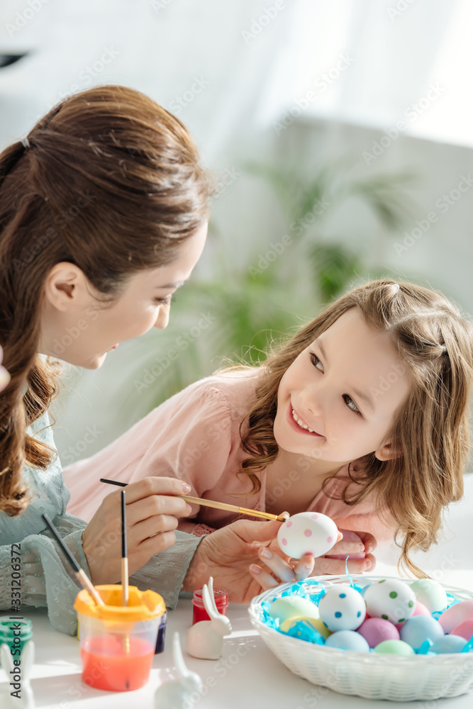 happy mother and cheerful daughter painting easter eggs happy mother and cheerful daughter painting easter eggs