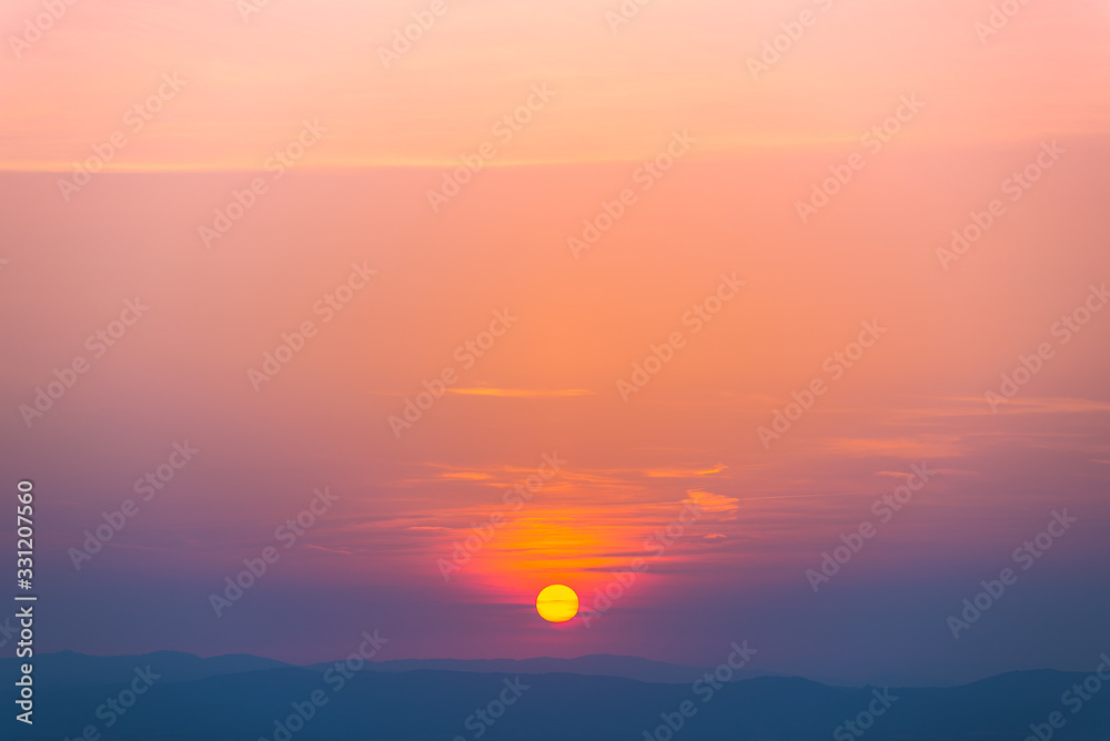 setting sun over over a silhouette of mountains, relaxing and peaceful atmosphere