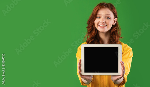 Cheerful Girl Showing Digital Tablet Empty Screen Standing In Studio