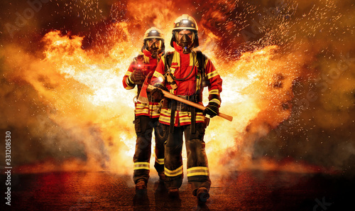 Zwei Feuerwehrmänner unter Atemschutz gehen durchs Feuer