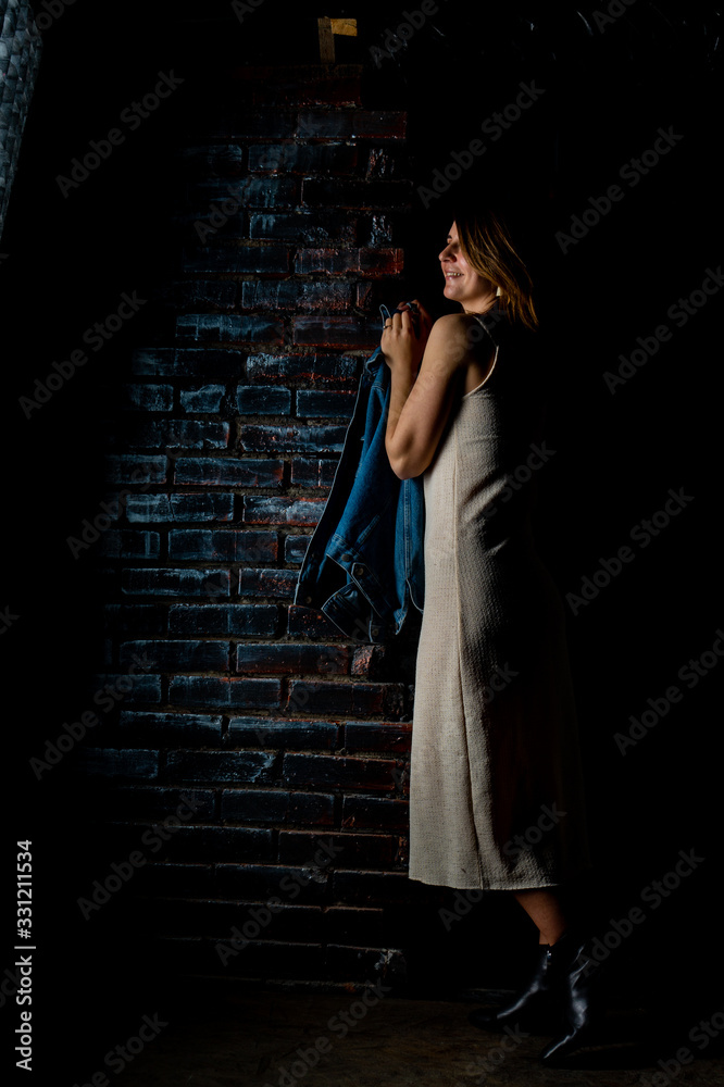 brunette girl in a green jacket and bra stands near the white brick wall. brunette girl in a green jacket and bra stands near the white brick wall.