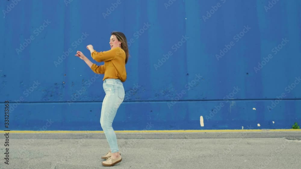 Young dancing woman in front of a blue wall Young dancing woman in front of a blue wall