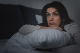 selective focus of dissatisfied woman having insomnia while lying on bed at night