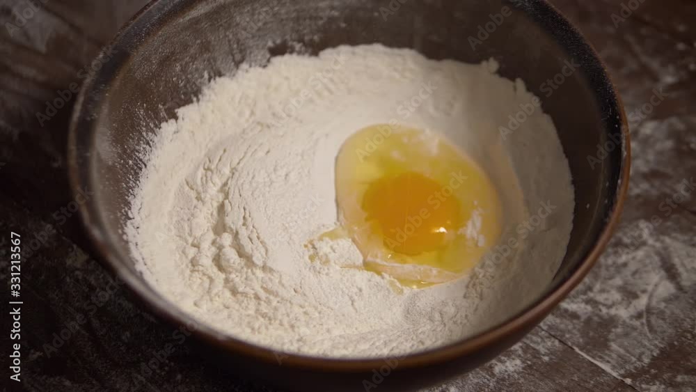 Egg falling into flour slow motion shot. Slow motion of egg falls on brown bowl with flour. Egg Yolk falls into flour in close up slow motion. Close up shot of egg falling in a bowl with flour. Egg falling into flour slow motion shot. Slow motion of egg falls on brown bowl with flour. Egg Yolk falls into flour in close up slow motion. Close up shot of egg falling in a bowl with flour.