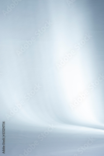 Shadows and beams of lights on a white studio backdrop.