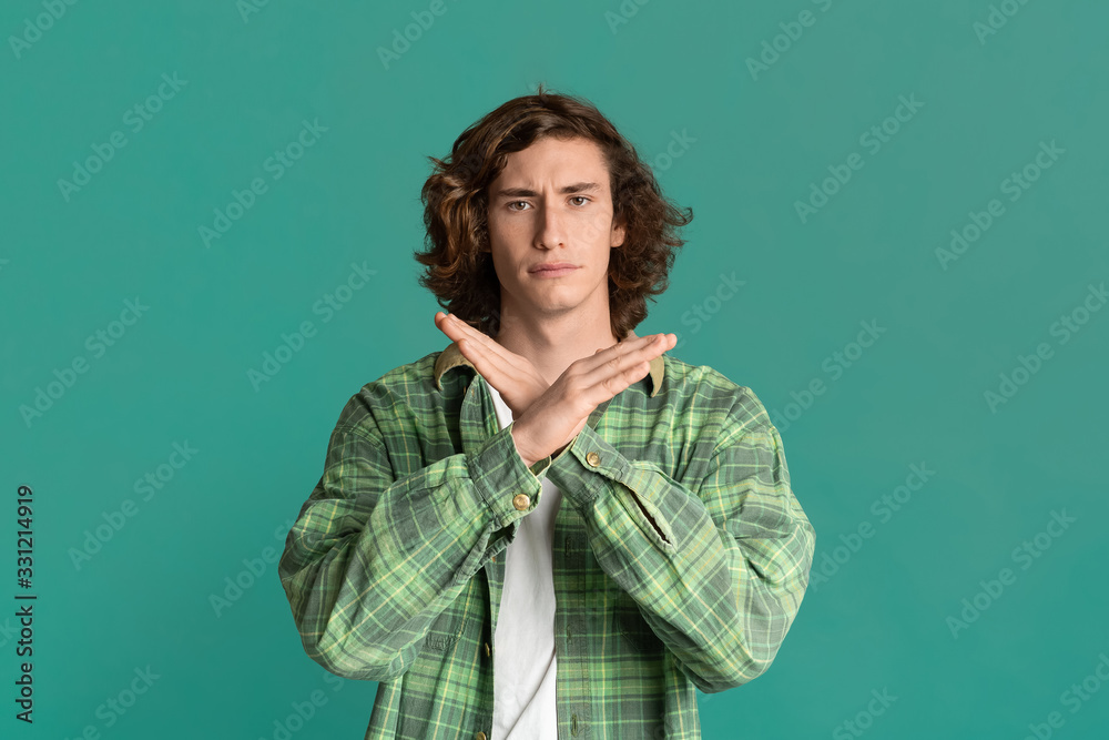 Serious millennial guy showing STOP or TIME OUT gesture on color background Serious millennial guy showing STOP or TIME OUT gesture on color background