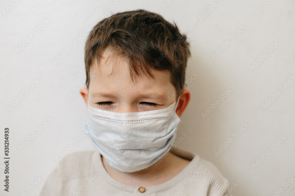 Crying toddler boy with medical mask on the face. Covid 2019 corona virus outbreak. Sad child isolated on white. Boy at home Crying toddler boy with medical mask on the face. Covid 2019 corona virus outbreak. Sad child isolated on white. Boy at home