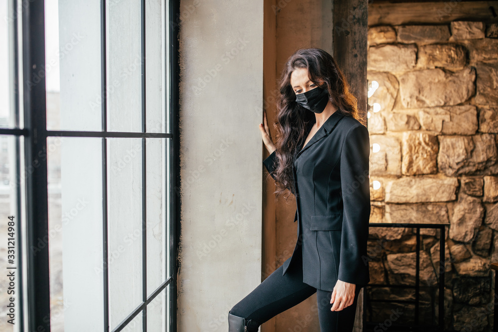 A woman in a medical mask looks out the window. A woman in a medical mask looks out the window.