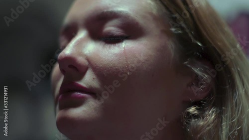 Slow motion shot of crying woman with a tear falling down her cheek photo