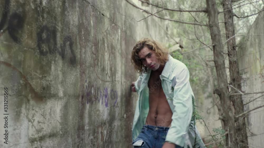 Slow motion shot of young man walking between walls Slow motion shot of young man walking between walls